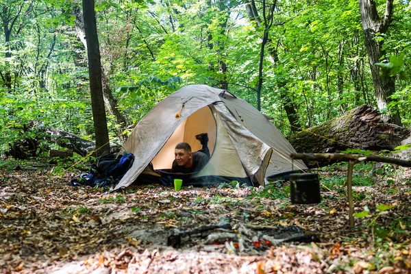 Bir şenlik ateşi ve ormandaki bir turist çadır, çadır turist dinleniyor.
