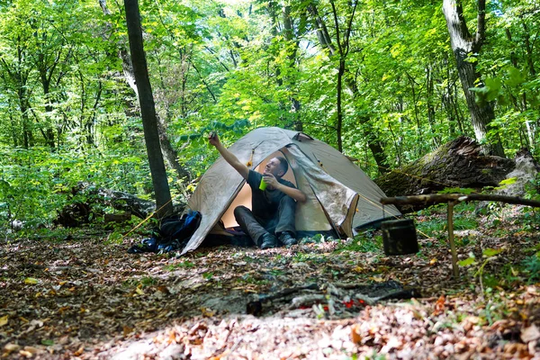 Bir şenlik ateşi ve ormandaki bir turist çadır, çadır turist dinleniyor.
