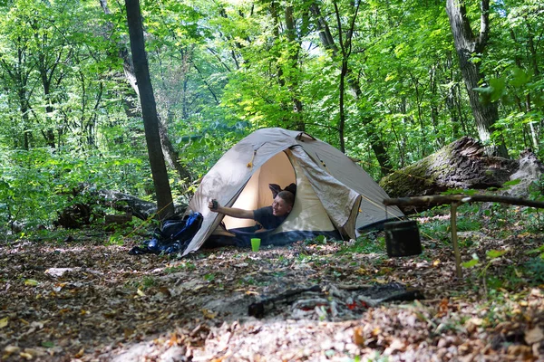 Bir şenlik ateşi ve ormandaki bir turist çadır, çadır turist dinleniyor.