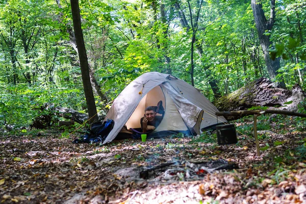 Bir şenlik ateşi ve ormandaki bir turist çadır, çadır turist dinleniyor.