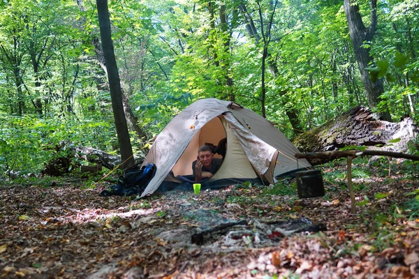 Bir şenlik ateşi ve ormandaki bir turist çadır, çadır turist dinleniyor.