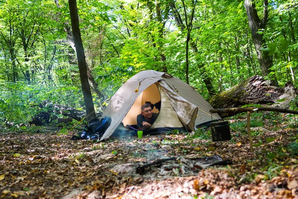 Bir şenlik ateşi ve ormandaki bir turist çadır, çadır turist dinleniyor.