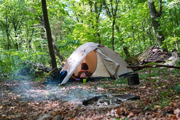 Bir şenlik ateşi ve ormandaki bir turist çadır, çadır turist dinleniyor.
