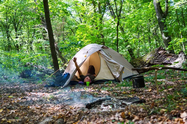 Bir şenlik ateşi ve ormandaki bir turist çadır, çadır turist dinleniyor.