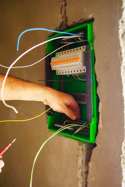 Hands electrical wiring is pulled through the hole in the wall of the drywall. — Stock Photo, Image