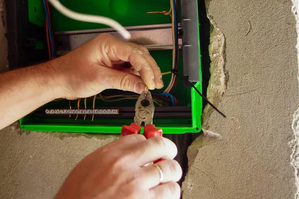 Hands electrical wiring is pulled through the hole in the wall of the drywall. — Stock Photo, Image