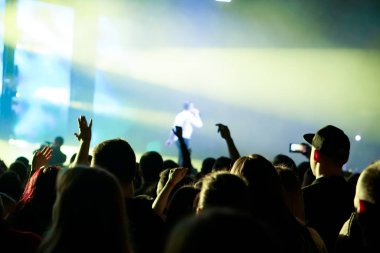 Seyirci bir Müzik Festivali ve sahne yukarıdan aşağı akış ışıklar kaldırdı elleriyle. Yumuşak odak, yüksek ISO, grenli görüntü.