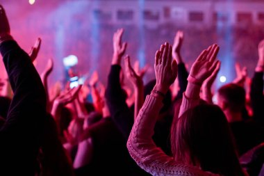 Seyirci bir Müzik Festivali ve sahne yukarıdan aşağı akış ışıklar kaldırdı elleriyle. Yumuşak odak, yüksek ISO, grenli görüntü.