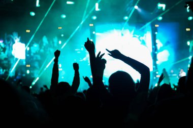 Seyirci bir Müzik Festivali ve sahne yukarıdan aşağı akış ışıklar kaldırdı elleriyle. Yumuşak odak, yüksek ISO, grenli görüntü.