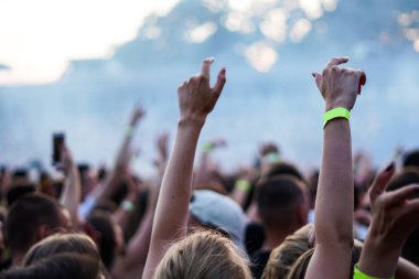 Seyirci bir Müzik Festivali ve sahne yukarıdan aşağı akış ışıklar kaldırdı elleriyle. Yumuşak odak, yüksek ISO, grenli görüntü.