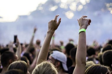 Seyirci bir Müzik Festivali ve sahne yukarıdan aşağı akış ışıklar kaldırdı elleriyle. Yumuşak odak, yüksek ISO, grenli görüntü.