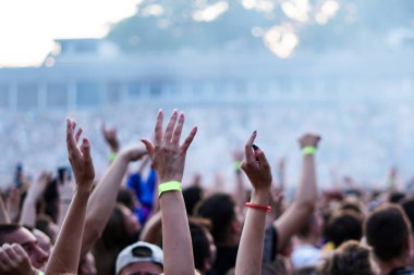 Seyirci bir Müzik Festivali ve sahne yukarıdan aşağı akış ışıklar kaldırdı elleriyle. Yumuşak odak, yüksek ISO, grenli görüntü.