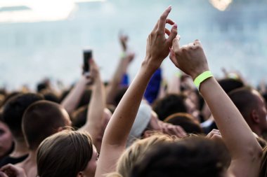 Seyirci bir Müzik Festivali ve sahne yukarıdan aşağı akış ışıklar kaldırdı elleriyle. Yumuşak odak, yüksek ISO, grenli görüntü.