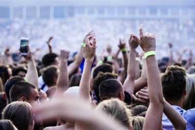 Seyirci bir Müzik Festivali ve sahne yukarıdan aşağı akış ışıklar kaldırdı elleriyle. Yumuşak odak, yüksek ISO, grenli görüntü.