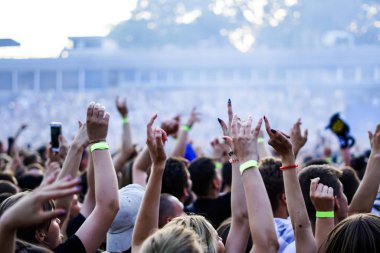 Seyirci bir Müzik Festivali ve sahne yukarıdan aşağı akış ışıklar kaldırdı elleriyle. Yumuşak odak, yüksek ISO, grenli görüntü.