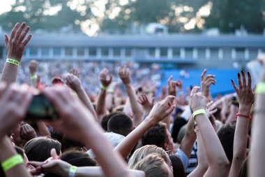 Seyirci bir Müzik Festivali ve sahne yukarıdan aşağı akış ışıklar kaldırdı elleriyle. Yumuşak odak, yüksek ISO, grenli görüntü.
