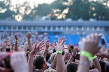 Seyirci bir Müzik Festivali ve sahne yukarıdan aşağı akış ışıklar kaldırdı elleriyle. Yumuşak odak, yüksek ISO, grenli görüntü.