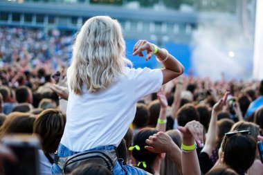 Yaz müzik festivalinde konser sırasında elleri havada dans eden, şarkı söyleyen ve müzik dinleyen kızlar.