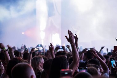 Seyirci bir Müzik Festivali ve sahne yukarıdan aşağı akış ışıklar kaldırdı elleriyle. Yumuşak odak, yüksek ISO, grenli görüntü.