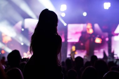 Yaz müzik festivalinde konser sırasında elleri havada dans eden, şarkı söyleyen ve müzik dinleyen kızlar.