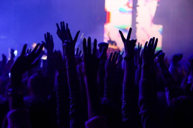 Seyirci bir Müzik Festivali ve sahne yukarıdan aşağı akış ışıklar kaldırdı elleriyle. Yumuşak odak, yüksek ISO, grenli görüntü.
