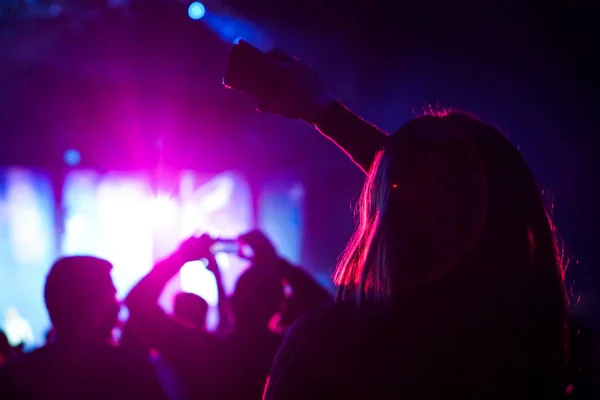 Seyirci bir Müzik Festivali ve sahne yukarıdan aşağı akış ışıklar kaldırdı elleriyle. Yumuşak odak, yüksek ISO, grenli görüntü. — Stok fotoğraf