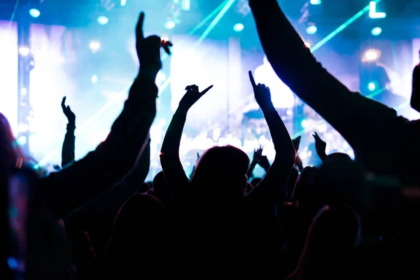 Publiek met handen ter sprake gebracht tijdens een muziekfestival en lichten streaming omlaag boven het werkgebied. Soft focus ondervraagt hoge Iso, korrelig beeld. — Stockfoto
