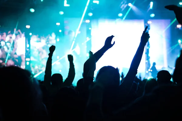 Аудиторія з піднятими руками на музичному фестивалі і вогні, що звучать зверху сцени. М'який фокус, висока ISO, сіре зображення . — стокове фото