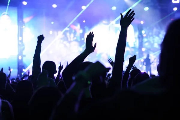 Público con las manos levantadas en un festival de música y luces que fluyen desde arriba del escenario. Enfoque suave, alta ISO, imagen granulada . —  Fotos de Stock