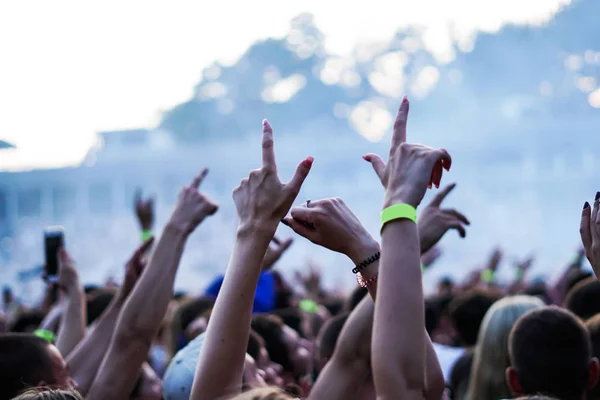 Ακροατήριο με χέρια αυξάνεται σε ένα φεστιβάλ μουσικής και την συνεχή ροή κάτω από πάνω από το στάδιο φώτα. Μαλακή εστίαση, υψηλό Iso, κοκκώδη εικόνα. — Φωτογραφία Αρχείου