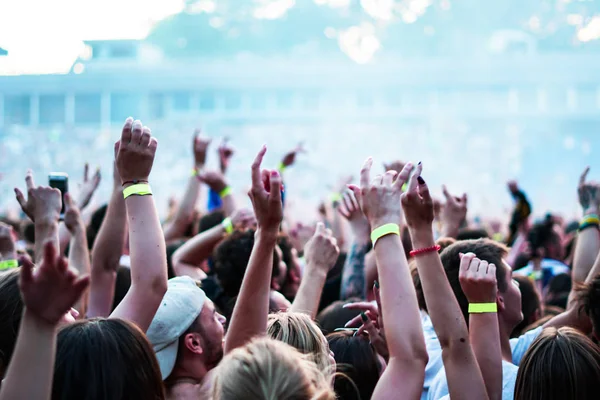 Público con las manos levantadas en un festival de música y luces que fluyen desde arriba del escenario. Enfoque suave, alta ISO, imagen granulada . — Foto de Stock