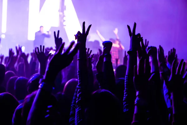 Зрители с поднятыми руками на музыкальном фестивале и огнями, струящимися сверху сцены. Низкая фокусировка, высокий ISO, красивое изображение . — стоковое фото
