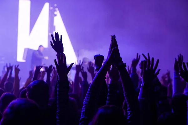 Publiczność z rąk podniesionych na festiwal muzyki i światła spływają z etapu. Nieostrość, wysoka czułość Iso, ziarnisty obraz. — Zdjęcie stockowe