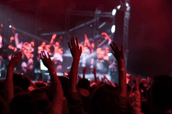 Crowd at a music concert, audience raising hands up