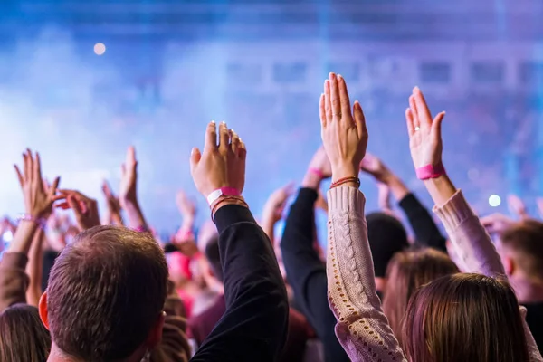 crowd cheering and hands raised at a live music concert