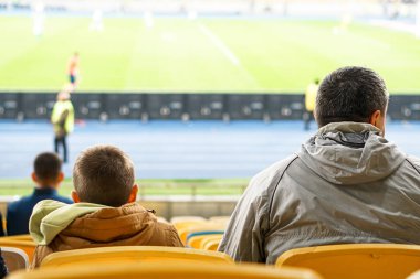 Aileler ve çocuklar stadyumdaki seyirciler için koltuklardan maçı izlerken