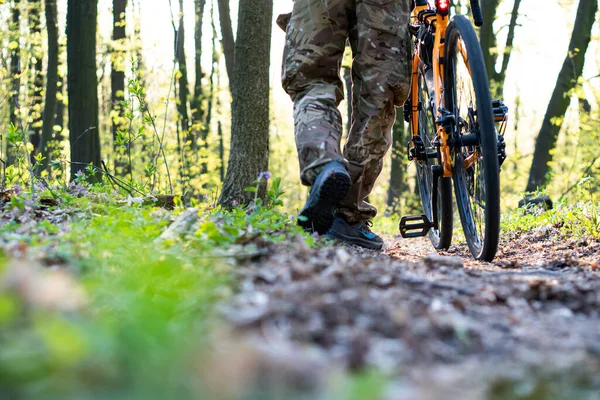 骑自行车的手里拿着自行车 沿着森林小径走着 — 图库照片