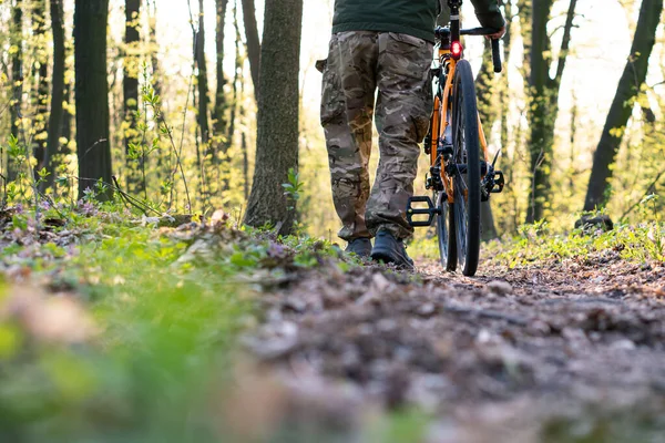 サイクリストは手に自転車を持ち森の小道を歩き — ストック写真