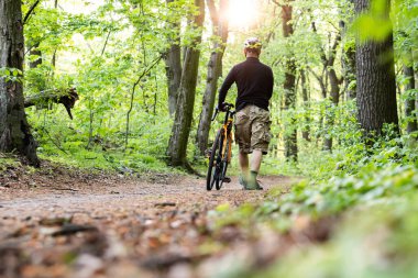 Bisikletçi ormanda bisikletle yürüyor