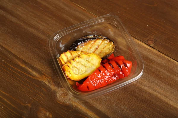 Grilled vegetables with small pieces of plastic container — Stock Photo, Image
