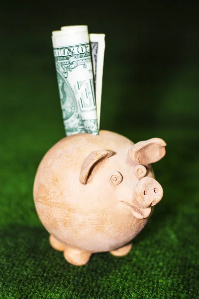 Vergi günü. Yeşil halı arka plan karşı bir dolar notu ile Piggy banka.