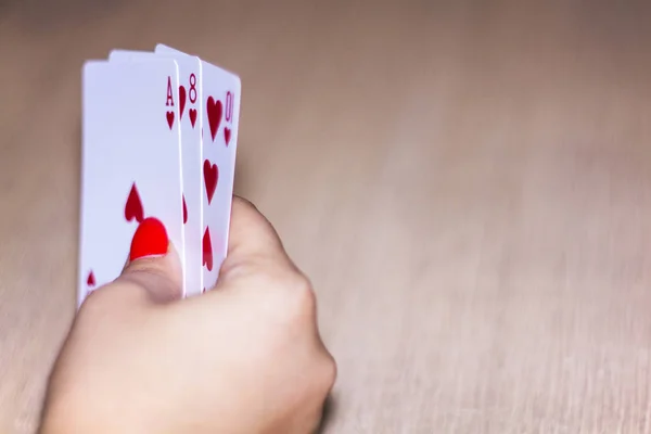 Poker. Kumarhane. Genç bir kadının elini kartları tutuyor.
