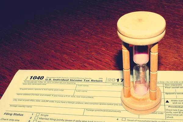 Vergi gün. Vergi form 1040 ve kum saati üzerinde ahşap bir tablodur.