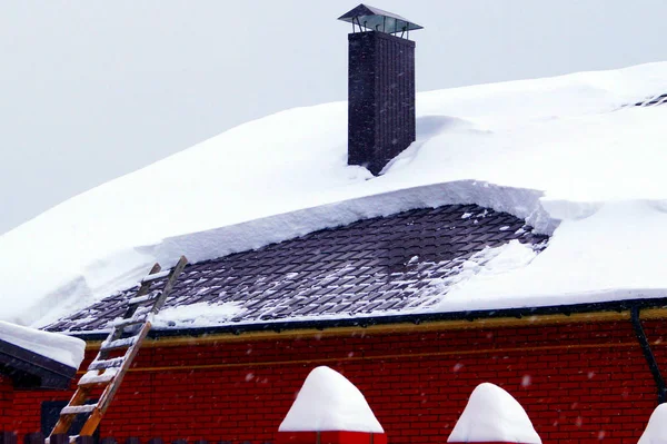 住宅の建物にはたくさんの雪が積もっていて 周りには大きな雪が降っています — ストック写真