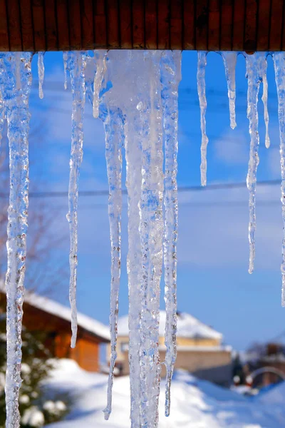 Birçok büyük ve keskin buz sarkıtları evin çatısında asılı. Seasons.