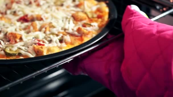 Pizza au four. les mains de l'homme dans les gants de cuisine mettre le plateau avec la pizza cuite leur donne le four. Cuisiner la pizza à la maison — Video