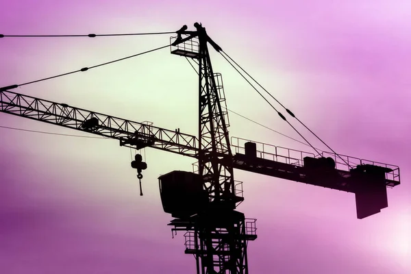 Silhouette of a crane a top building construction. the background of the sunset sky — Stock Photo, Image