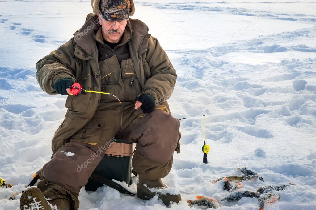 man is fishing from a hole on ice. Winter fishing.