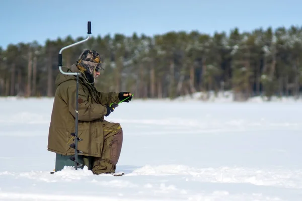 氷の湖で冬に釣りをする男は — ストック写真