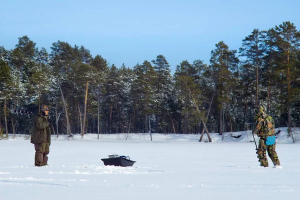 冬の森を背景に冬の湖で漁をしている漁師たちは — ストック写真